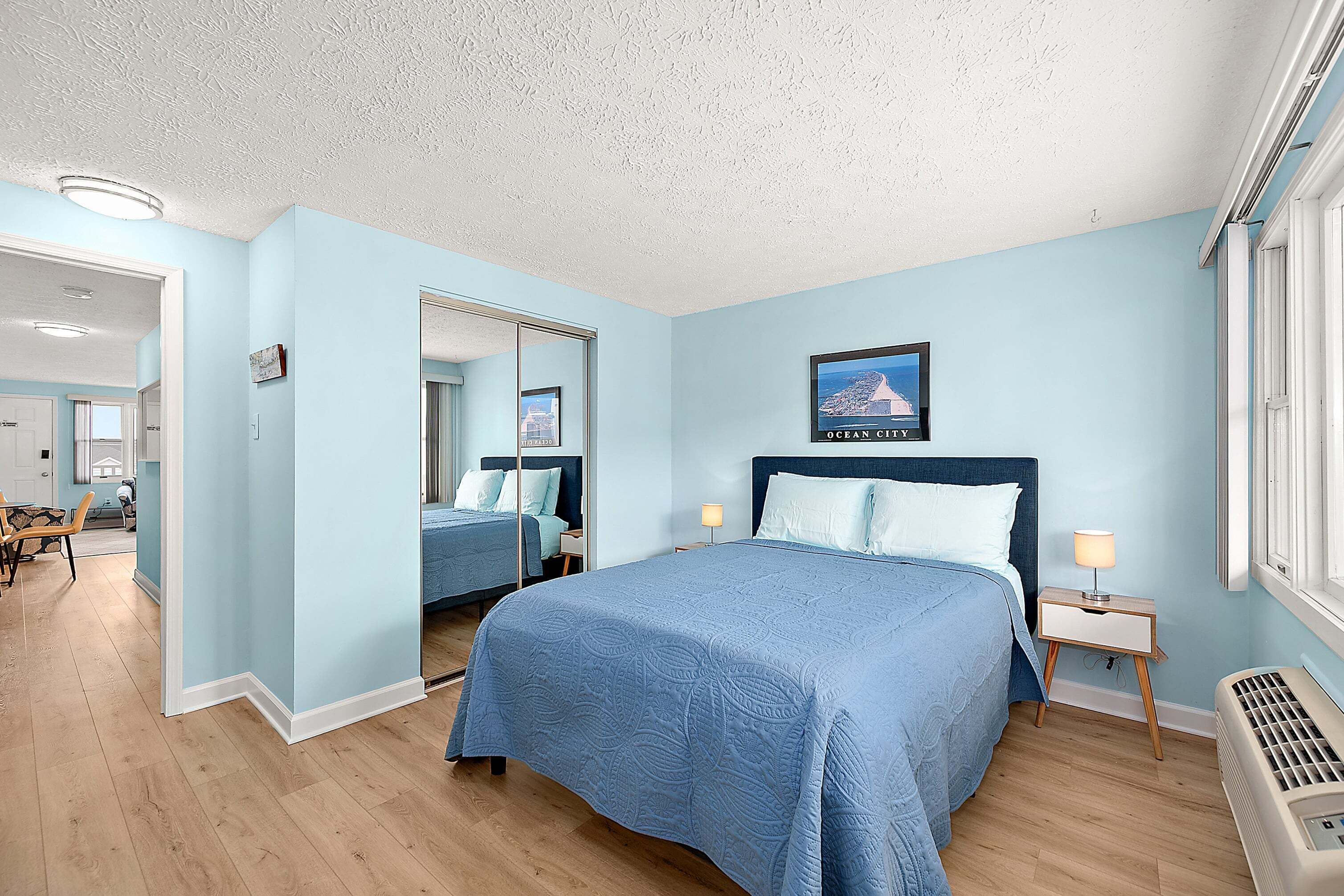 Une chambre à coucher avec un lit, des tables de chevet, un miroir et un tableau au mur.