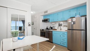 Une cuisine moderne avec des meubles bleus, des appareils en acier inoxydable et un coin repas blanc.