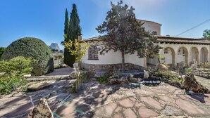A building with a stone facade, a circular window, and a garden with rocks and plants. - VILLA MARIA - Villa with sea views and private pool (Calpe)