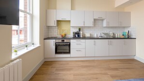 A modern kitchen with white cabinets, a built-in oven, and a window with potted plants. - Apartment 7 Isabella House Hereford (Hereford)