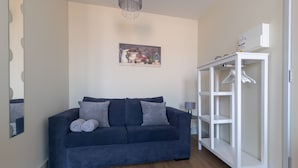 A modern living room with a dark blue sofa, a white shelving unit, and a wooden floor. - Apartment 7 Isabella House Hereford (Hereford)
