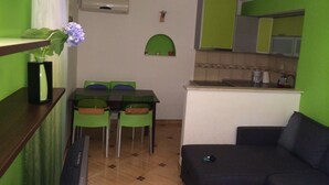 Un espace de vie compact comprenant un coin repas, une kitchenette et un canapé.