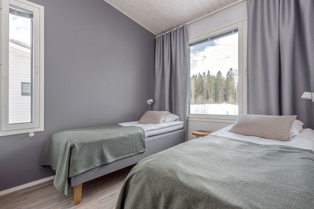 Un dormitorio con dos camas, paredes grises y una ventana con cortinas.