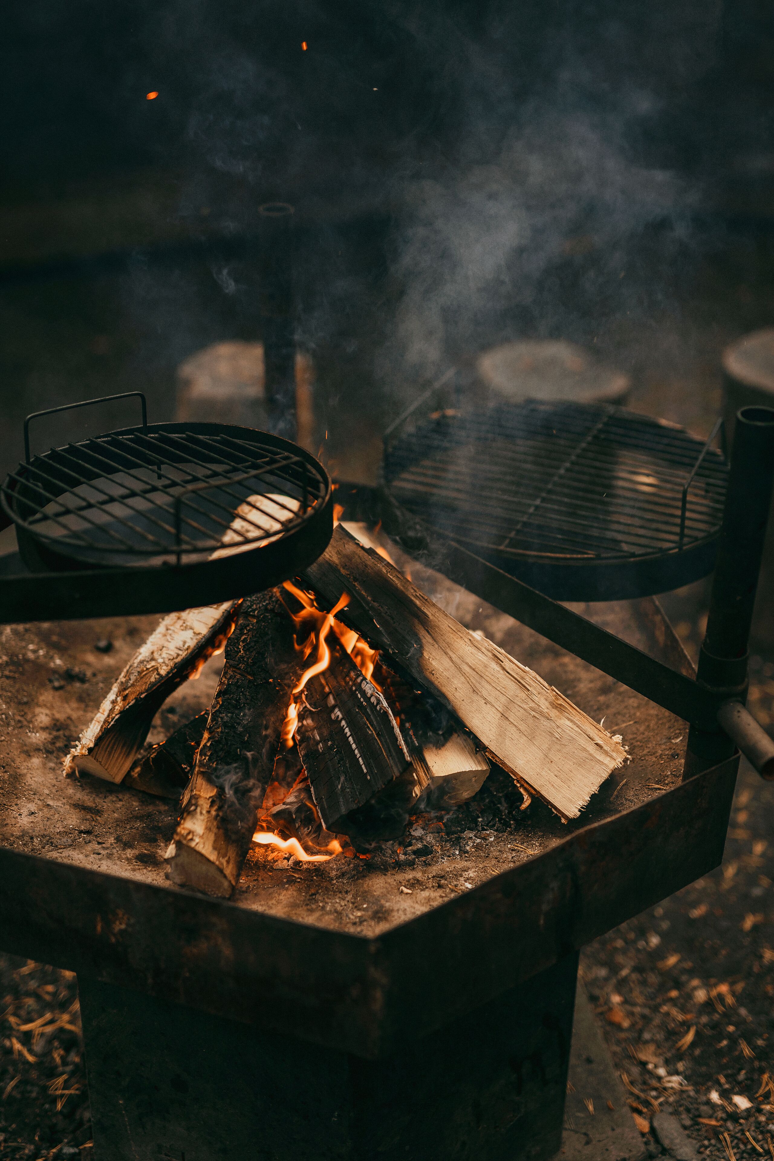 Un barbecue portatif doté de deux grilles au-dessus d’un foyer.