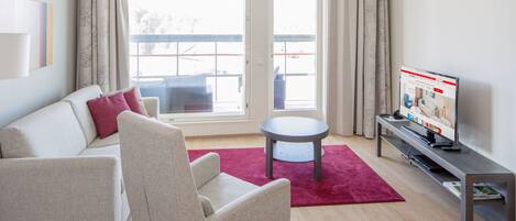 A modern living room with a sofa, armchair, and a small table.