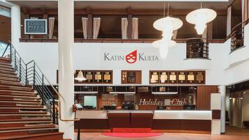 A modern interior with a reception desk, a staircase, and a sign for 'Katin Kulta'.