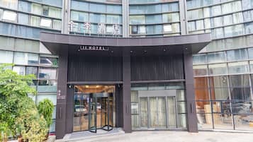 A modern hotel entrance with a revolving door, large glass windows, and a sign reading "JI HOTEL".