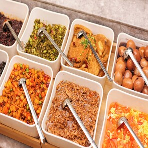 A buffet with various dishes in white trays, including a salad, a meat dish, and a dessert. - Ji Hotel (Hangzhou)