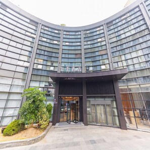 A modern hotel with a curved facade, large glass windows, and a prominent entrance. - Ji Hotel (Hangzhou)