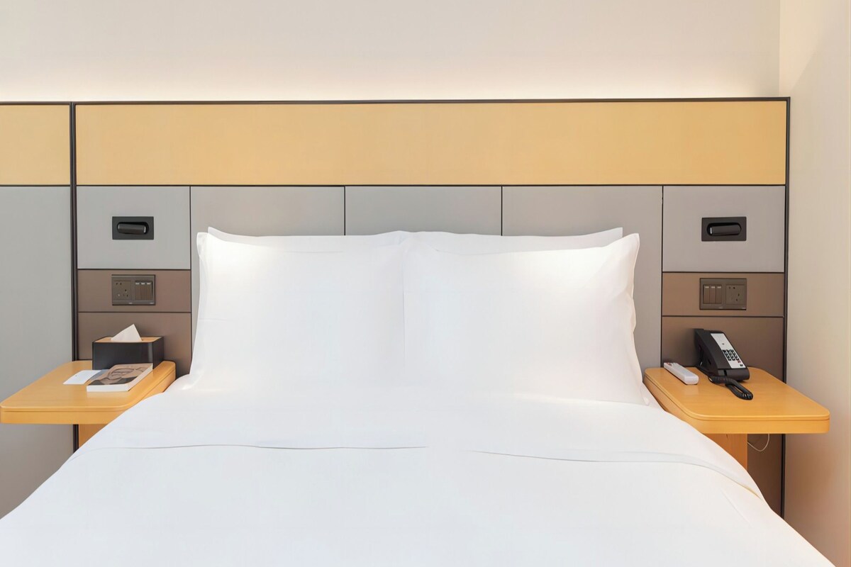 A hotel room with a bed, two bedside tables, a telephone, and a lamp.