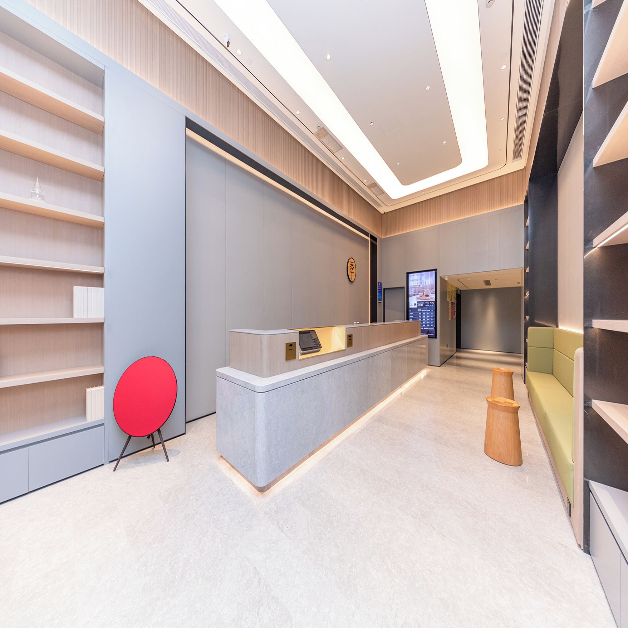 A modern reception area with a counter, a digital screen, and a seating area.