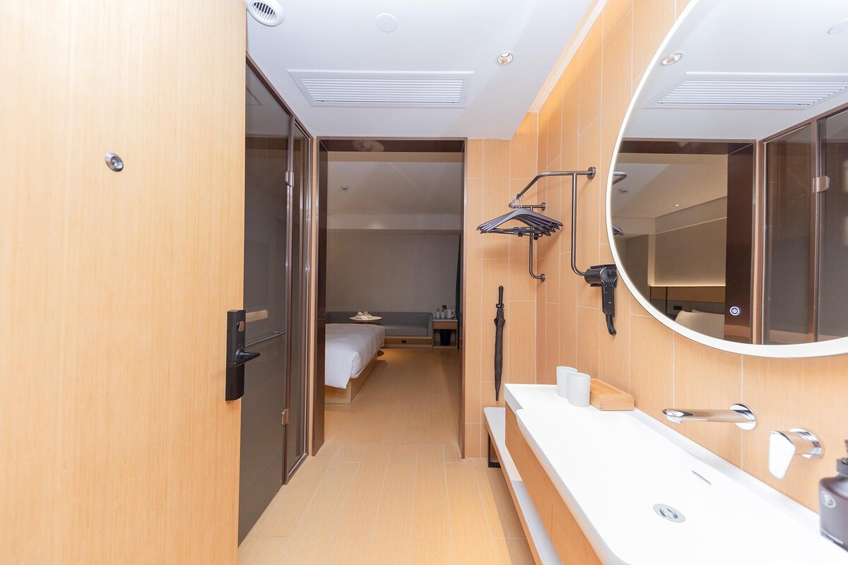 A modern bathroom with a large mirror, a sink, and a shower area.