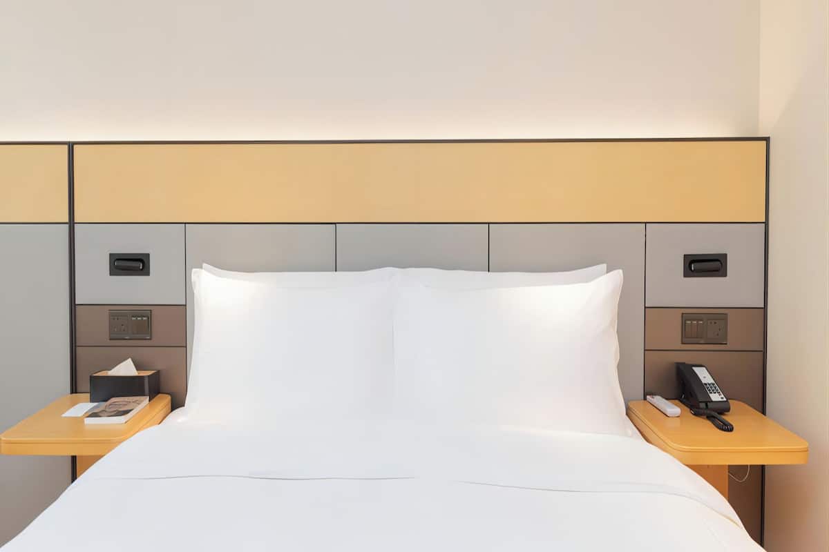Et hotelværelse med en seng, to sengeborde, en telefon og en lampe.