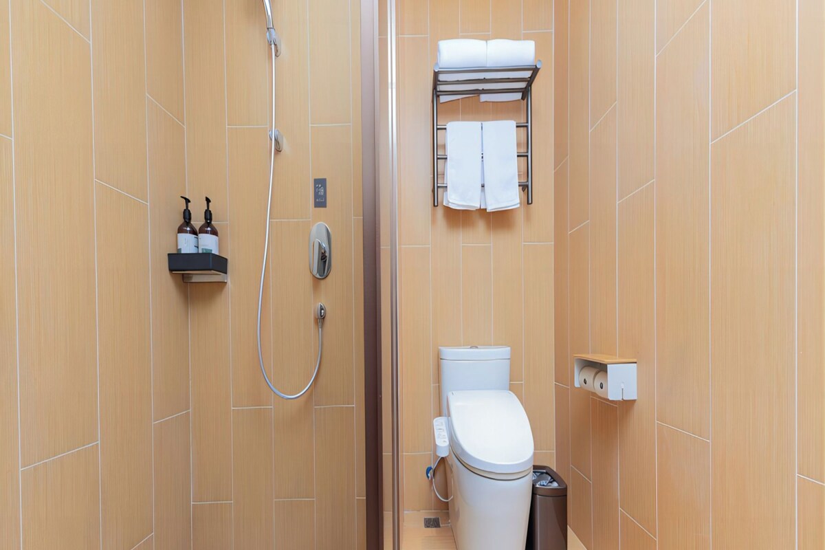 A compact bathroom with a shower, toilet, and towel rack.