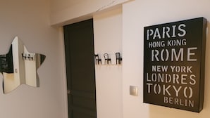 Een gang met een deur en een bord aan de muur met daarop een lijst van grote steden.