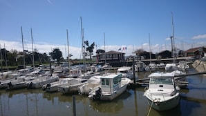 Een jachthaven met verschillende boten afgemeerd, een gebouw met een vlag en een heldere lucht.