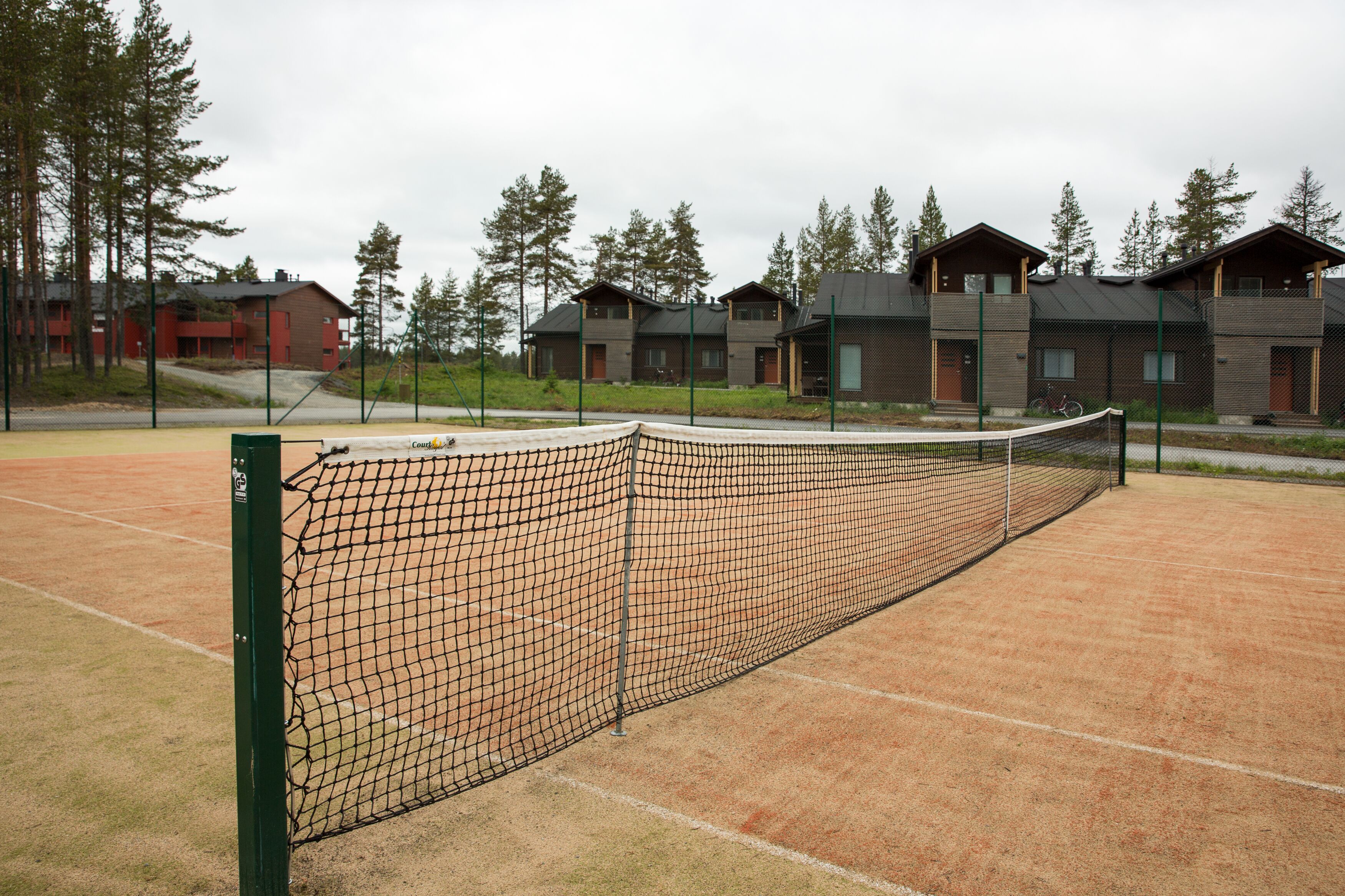 A tennis court with a net, surrounded by buildings with multiple windows and balconies.