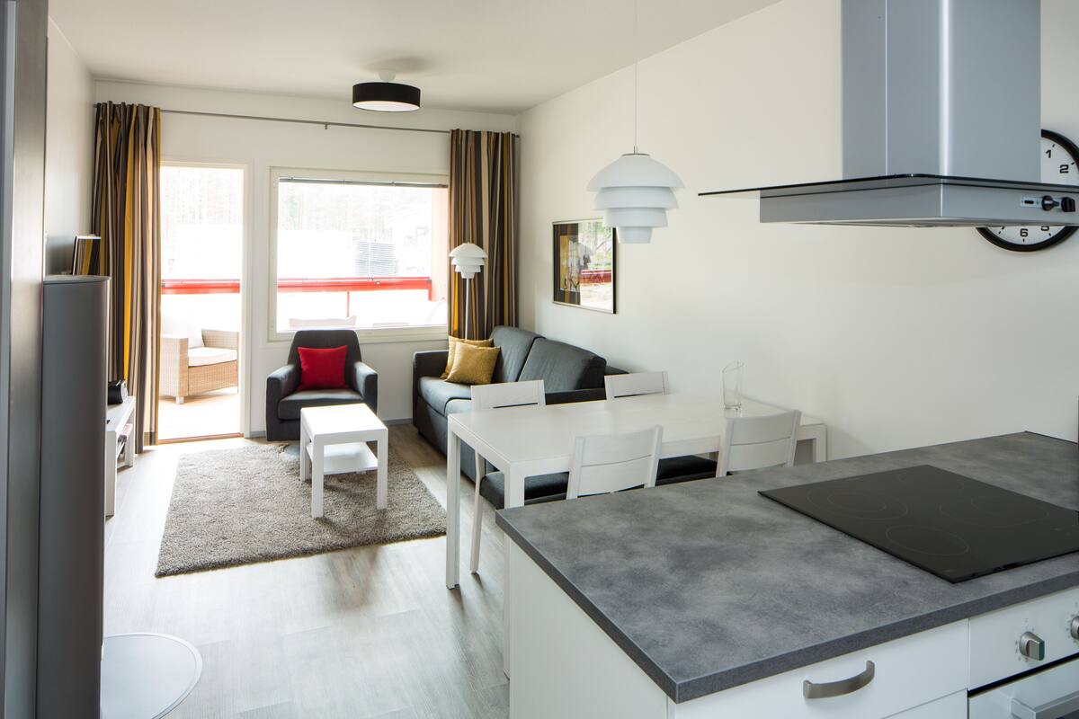 Una cocina moderna con estufa integrada, armarios blancos y encimera gris.