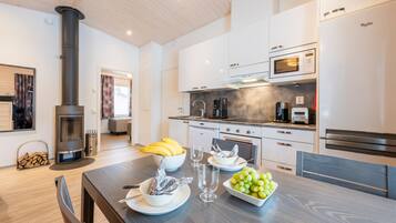 A modern kitchen with white cabinets, a black stove, and a dining area with a wooden table set for a meal.