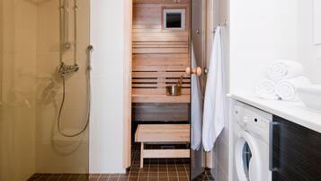 Un baño pequeño con ducha, inodoro y lavadora.