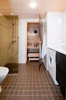 A compact bathroom with a shower, toilet, and washing machine.
