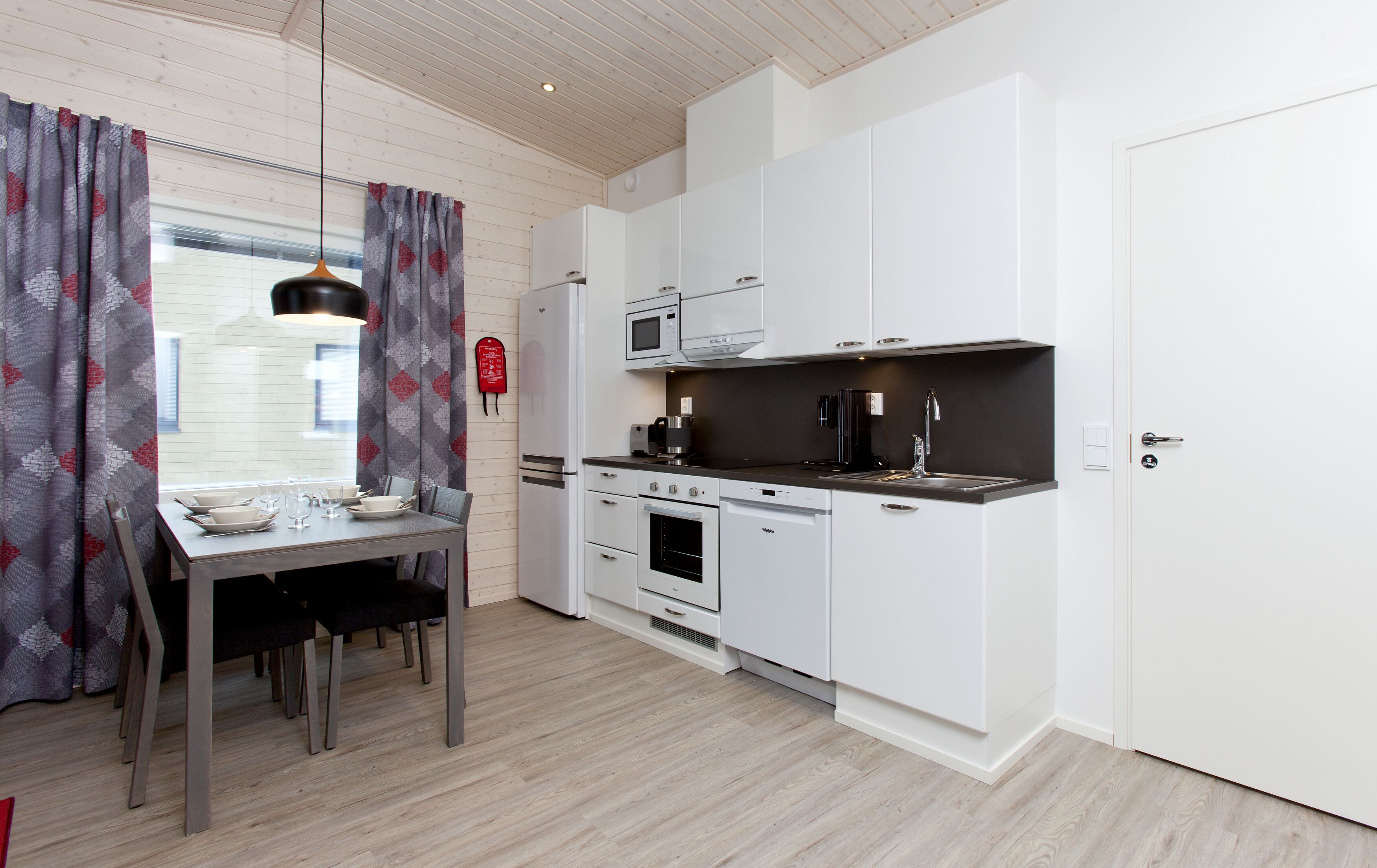 A modern kitchen with white cabinetry, a built-in oven, and a black countertop.