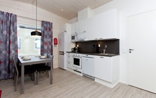 A modern kitchen with white cabinetry, a built-in oven, and a black countertop.