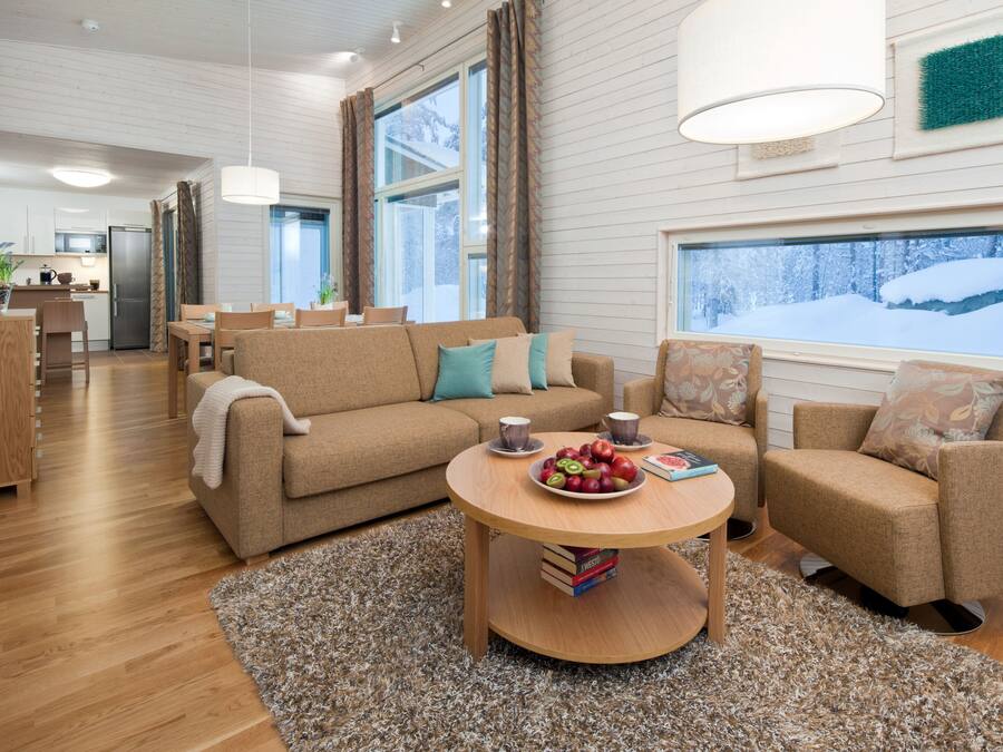 A modern living room with a sofa, armchairs, a coffee table, and a view of a snowy landscape through large windows.