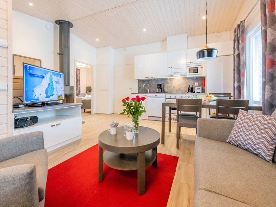 Ein modernes Wohnzimmer mit Fernseher, einem runden Couchtisch mit roten Akzenten und einer Couch.