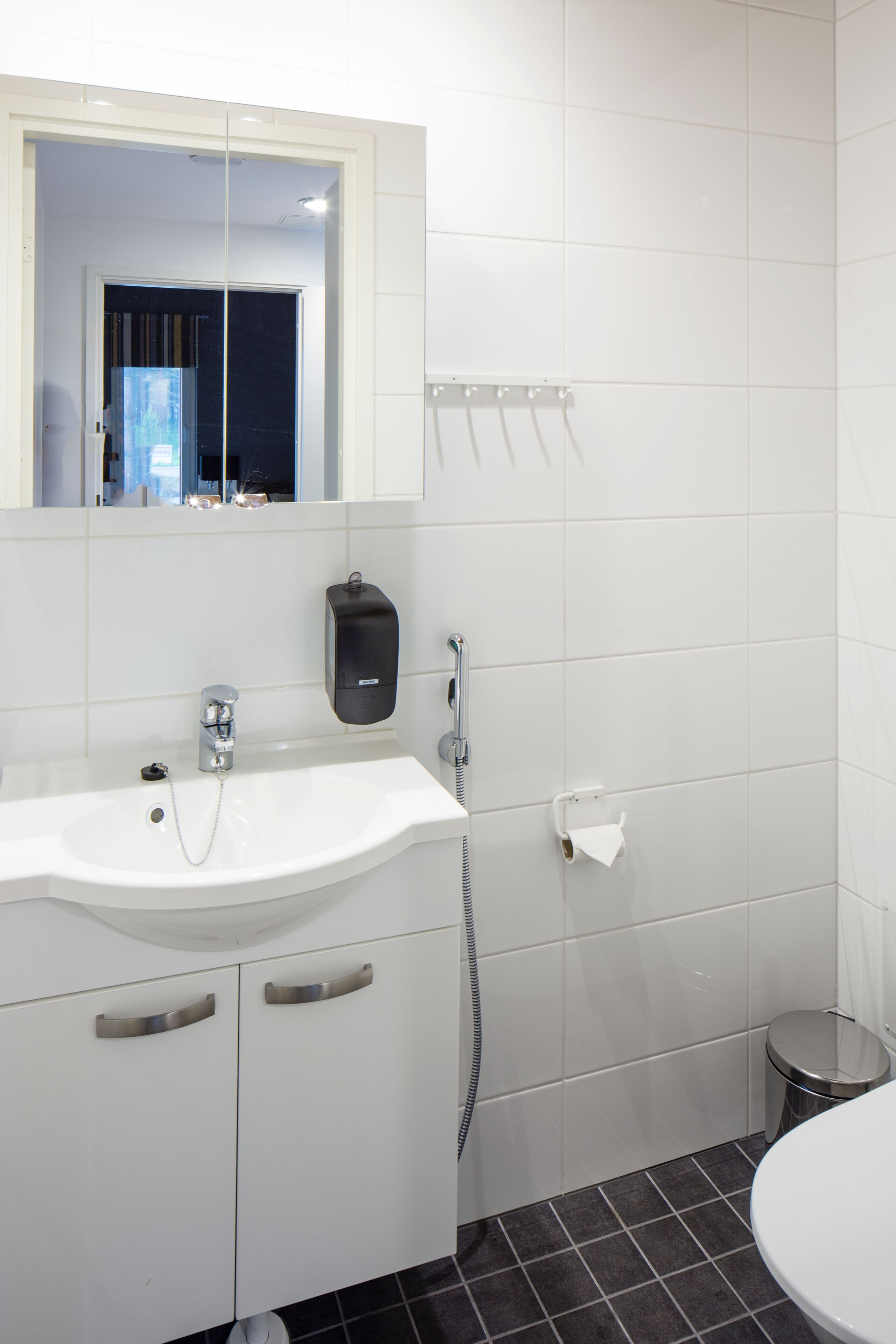 Ein modernes Badezimmer mit Waschbecken, Spiegel und Fliesenwänden.