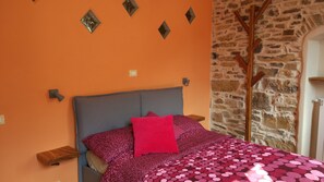 Ein Schlafzimmer mit Steinwand, einem Bett mit gemustertem Überwurf und dekorativen Wandleuchten.