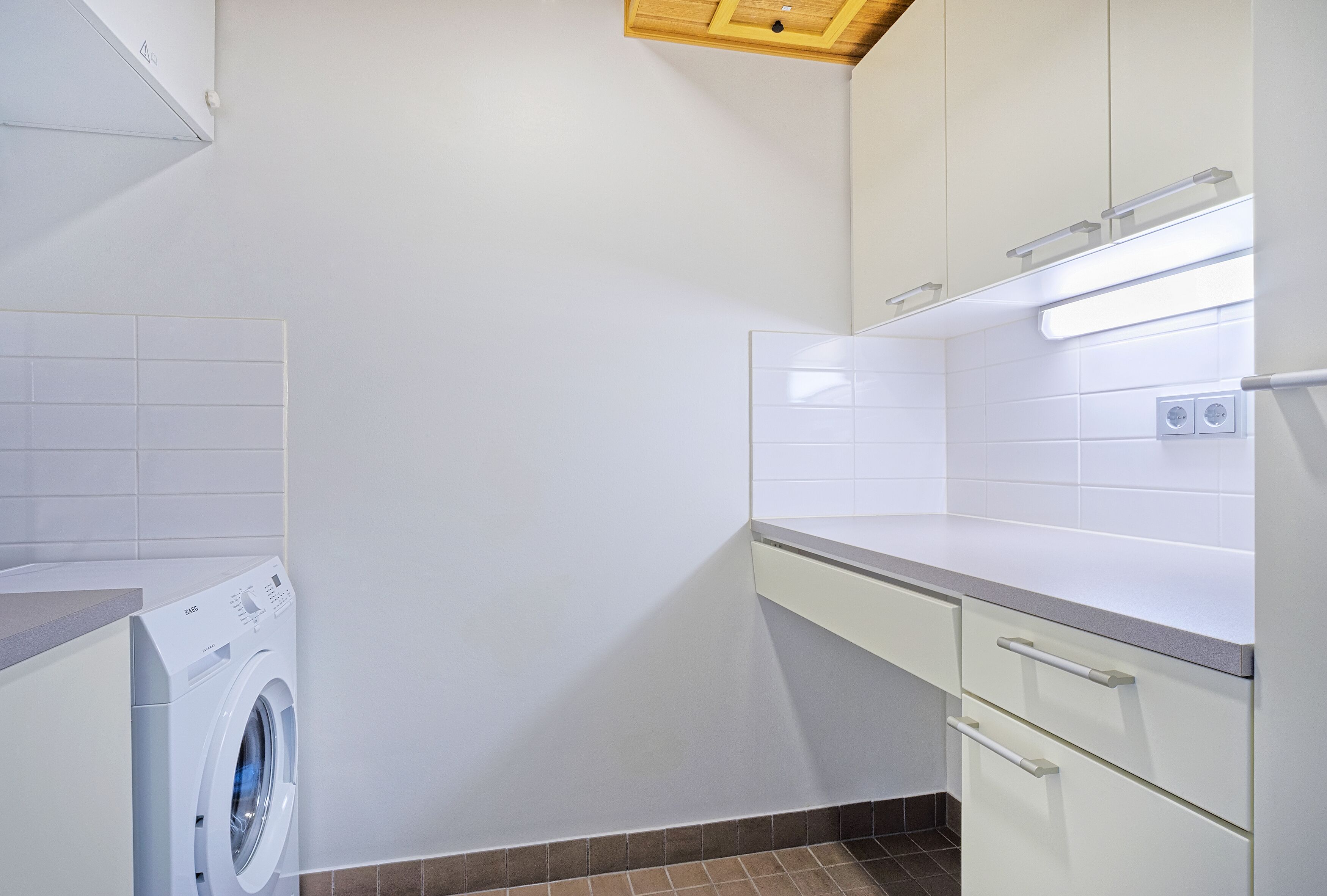 A compact laundry room with a washing machine, a countertop, and cabinets.