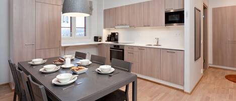A modern kitchen with wooden cabinets, a built-in oven, and a microwave.