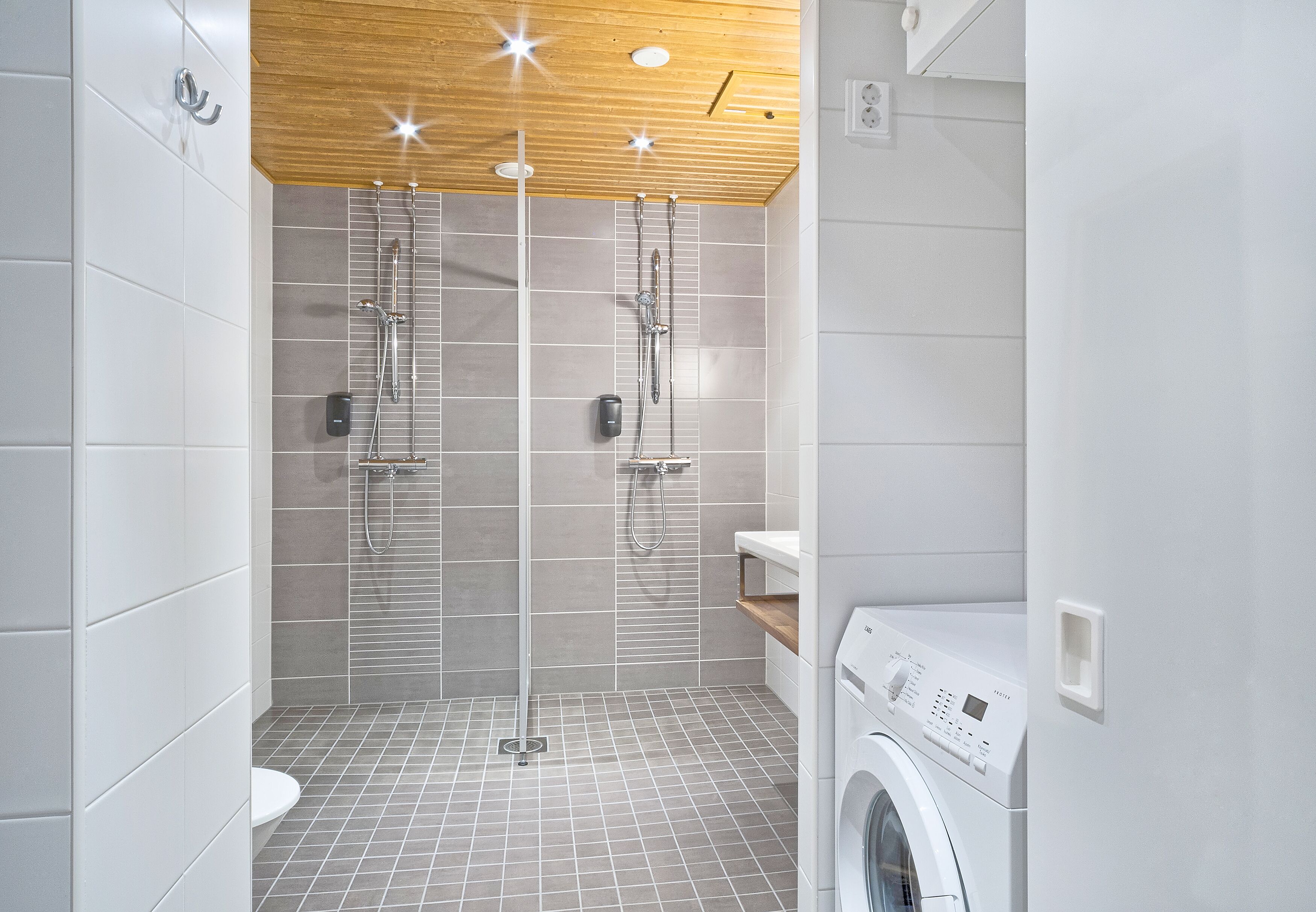 Ein modernes Badezimmer mit Dusche, Toilette und Waschmaschine.