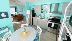 Una cocina compacta con zona de comedor, que incluye un refrigerador, estufa, pileta y alacenas.