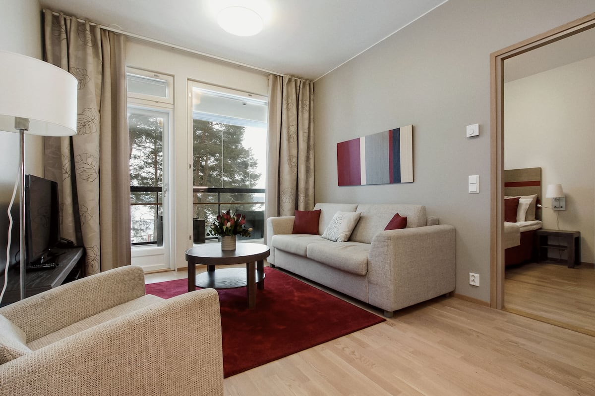 A living room with a sofa, a coffee table, a TV, and a window with curtains.