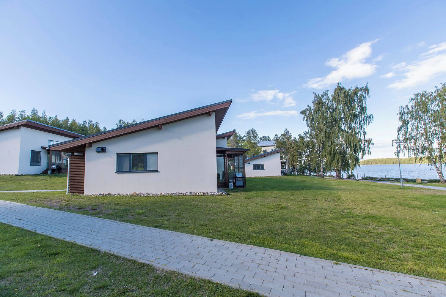 A modern two-story house with a flat roof, large windows, and a paved driveway.