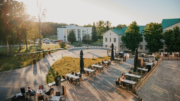 An outdoor patio area with tables and chairs, surrounded by buildings and trees.