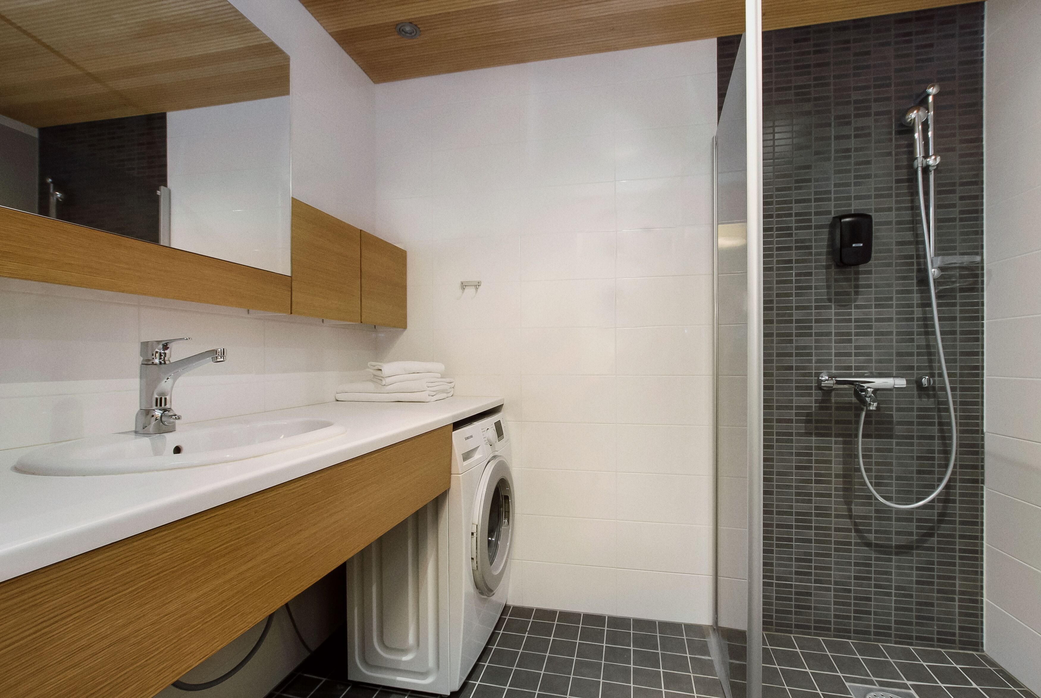Un baño moderno con lavamanos, espejo y lavadora.