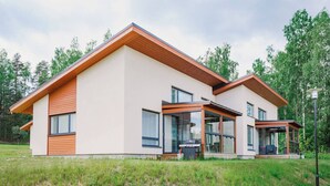 A modern two-story house with a large glass window and a wooden deck.