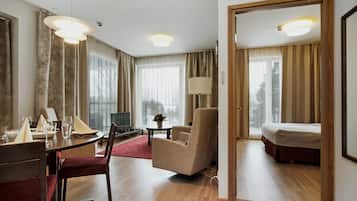 A hotel room with a dining area, a bed, and a large window with curtains.