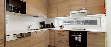 Una cocina moderna con armarios de madera, un lavavajillas Bosch y un ventanal con vistas.