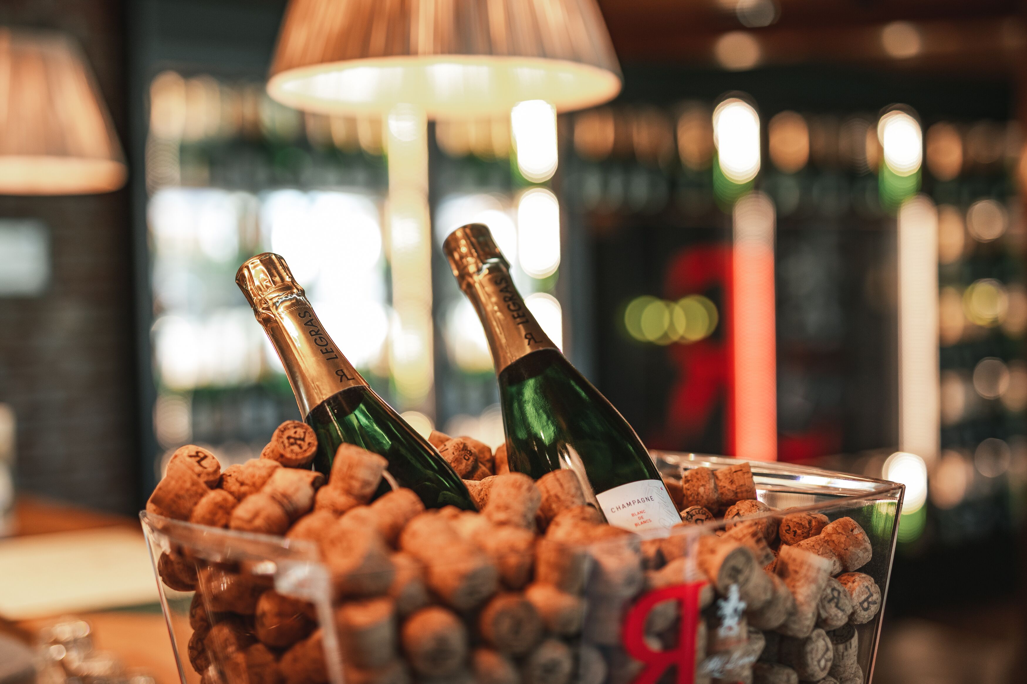 Two champagne bottles in a glass container filled with wine corks.