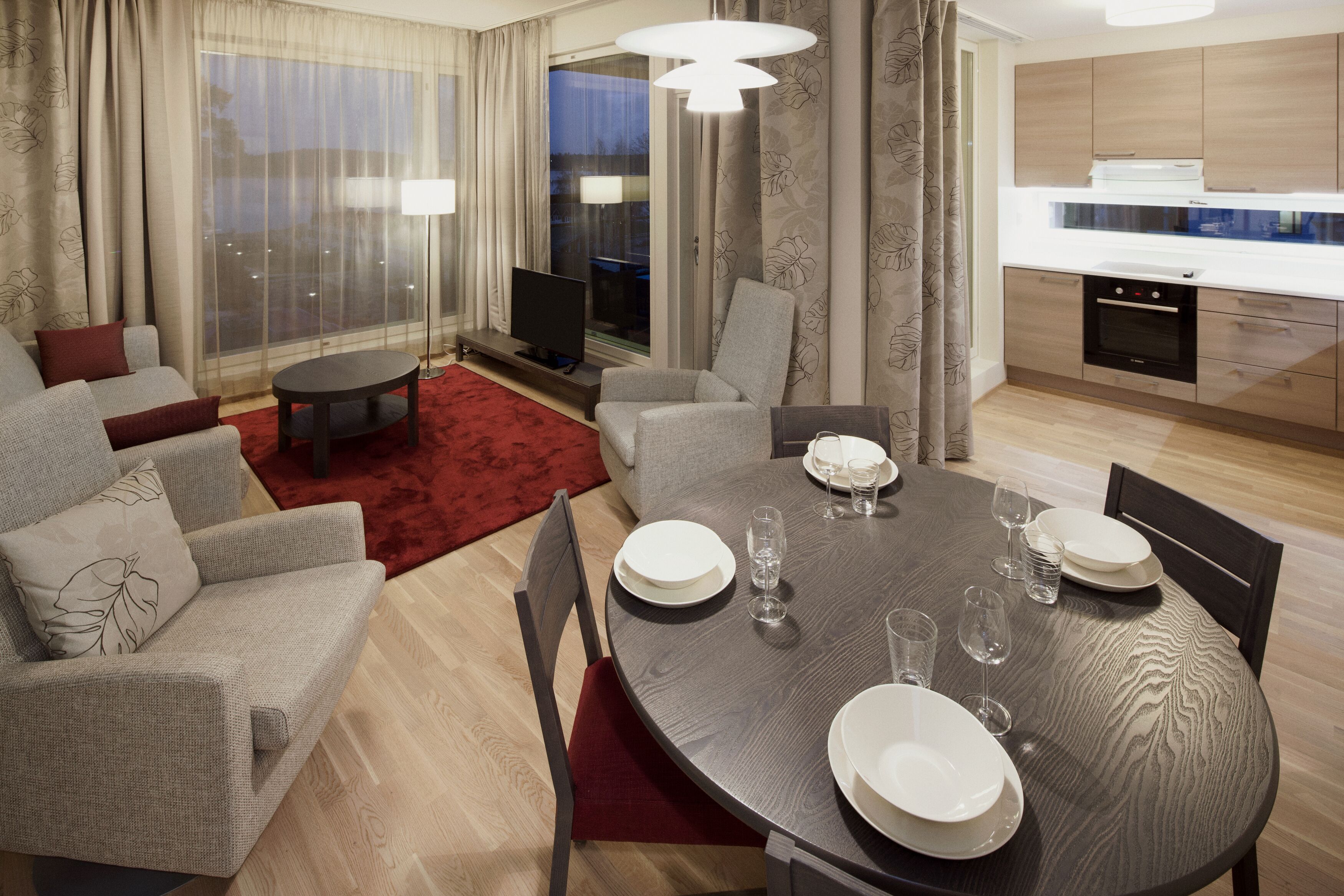 Un salon moderne comprenant un coin repas, de grandes fenêtres et une cuisine.