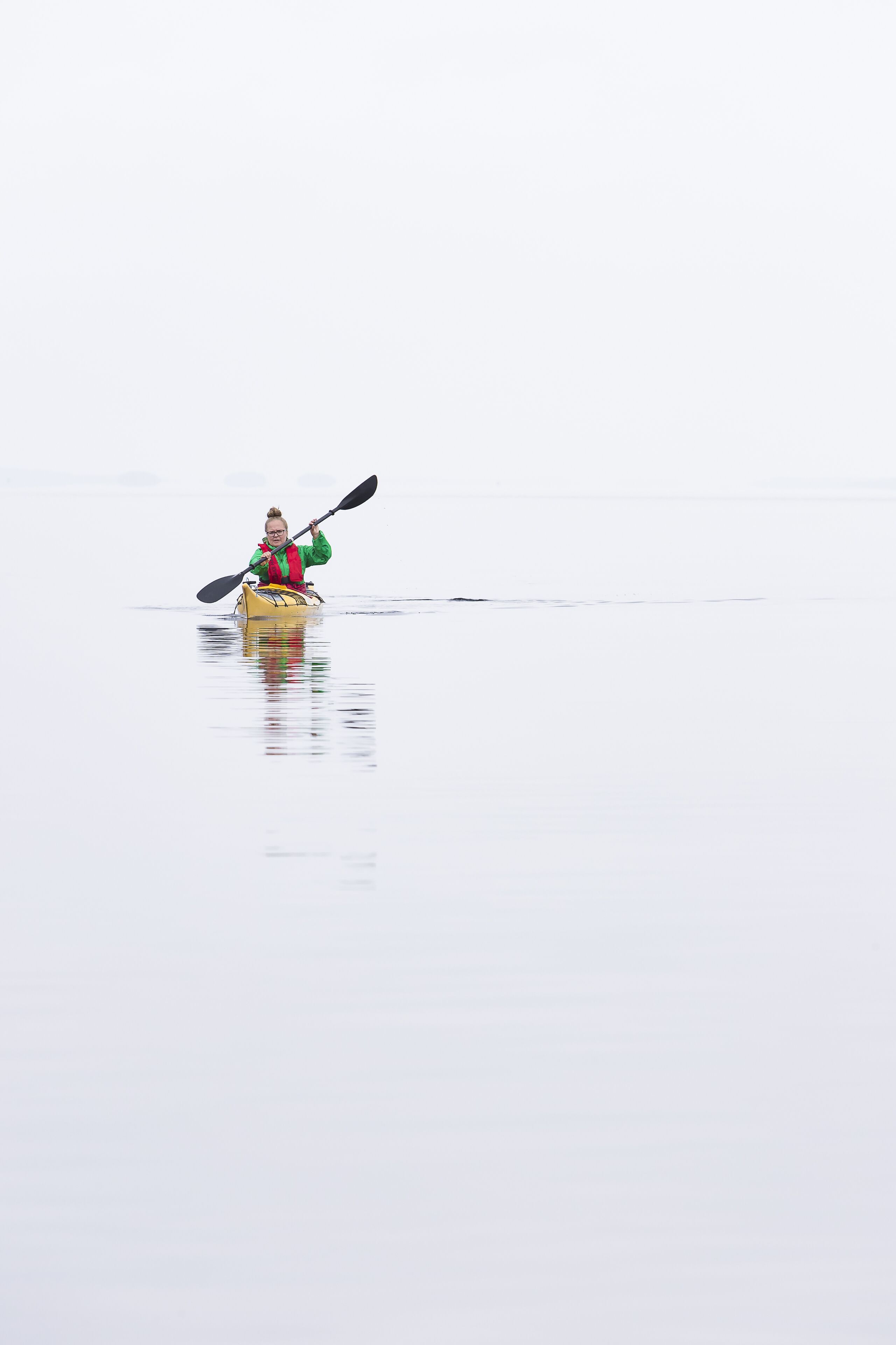 A person kayaking on a calm body of water.