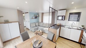 Een moderne, compacte woonruimte met een eethoek, kitchenette en een zithoek met een bank.