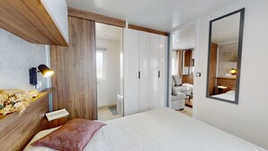 Een slaapkamer met een bed, nachtkastje, lamp en een grote spiegel.
