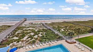 A beachside resort with a swimming pool, lounge chairs, and a wooden pier leading to the beach. - Oceanfront Condo with Oceanside Pool and Private Fishing Pier Access by RedAwning (Fernandina Beach)