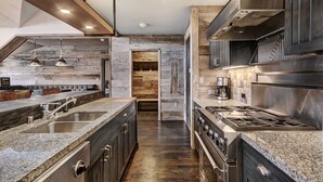 A modern kitchen with granite countertops, stainless steel appliances, and a wooden accent wall.