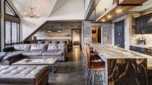 A modern kitchen with a marble countertop, a built-in oven, and a hanging light fixture.